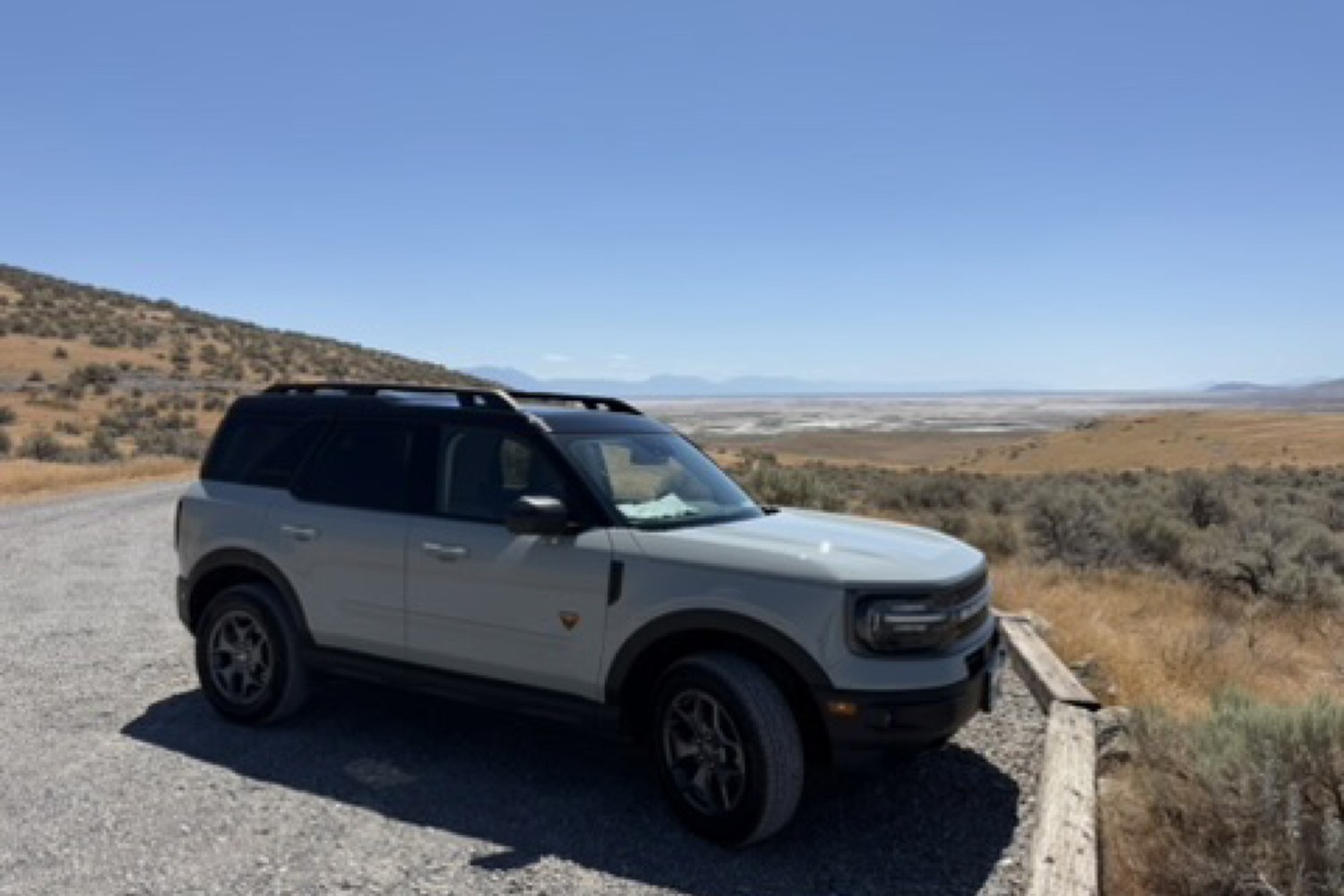 Daisy, a sage-green Ford Bronco Sport, parked on a ridge above a wide desert valley